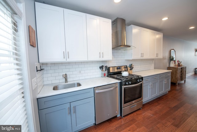 kitchen featuring a sink, tasteful backsplash, dark wood-style floors, appliances with stainless steel finishes, and wall chimney range hood