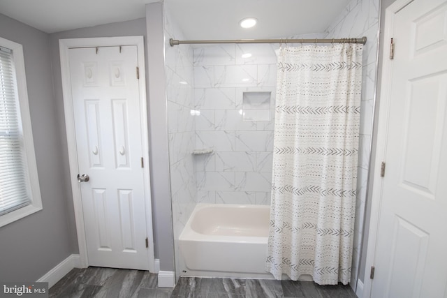 full bath featuring baseboards, wood finished floors, and shower / tub combo