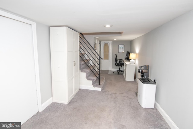 foyer with baseboards, light carpet, and stairs