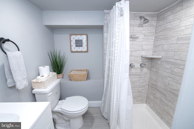 bathroom with a shower stall, toilet, vanity, and baseboards