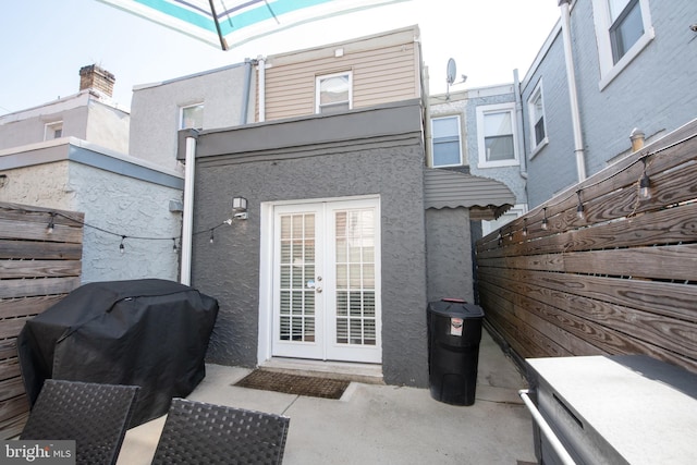 back of property with french doors, fence, and stucco siding