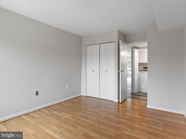 unfurnished bedroom with light wood finished floors, washer / dryer, a closet, and baseboards