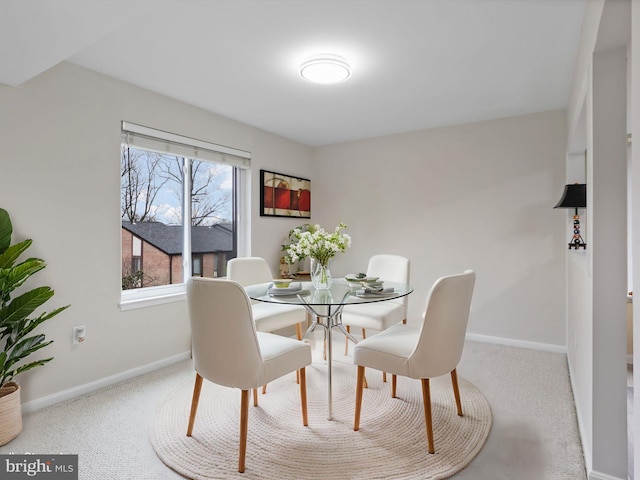 carpeted dining room featuring baseboards