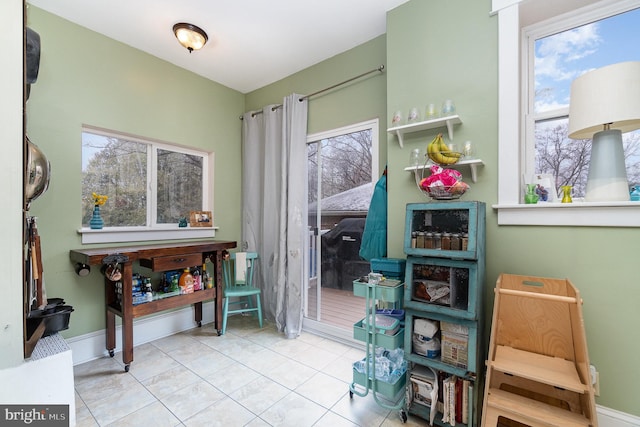 living area with tile patterned floors, a healthy amount of sunlight, and baseboards