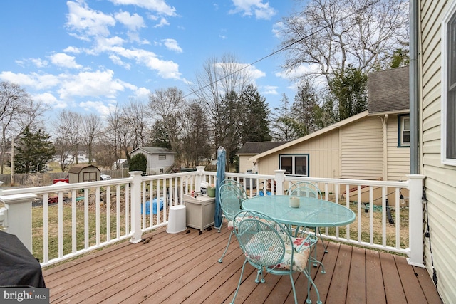 wooden terrace with an outbuilding, a shed, and outdoor dining area