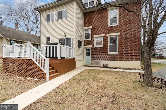 rear view of property with a yard, brick siding, and a deck