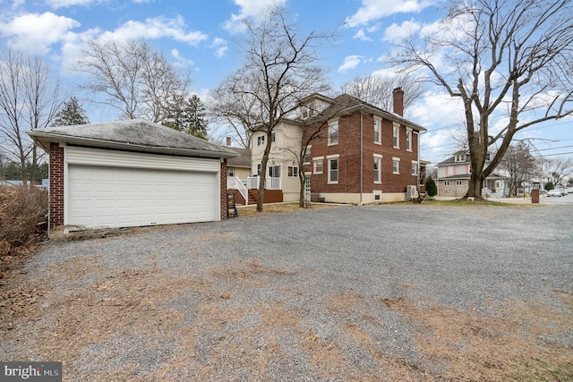 view of side of home featuring a garage, brick siding, and a chimney