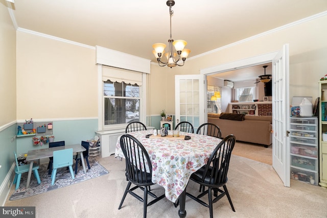 carpeted dining space with ceiling fan with notable chandelier and ornamental molding