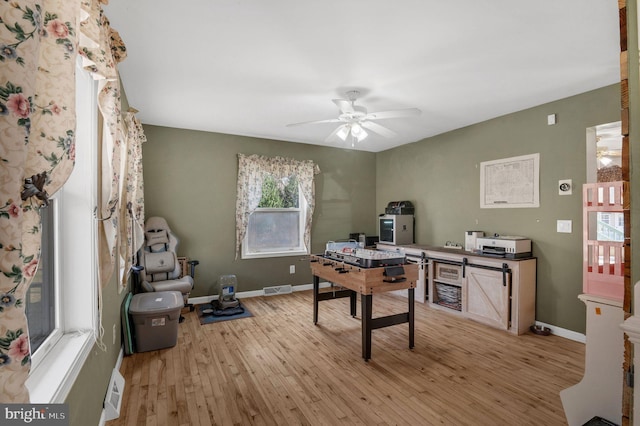 office space with light wood-type flooring, baseboards, visible vents, and a ceiling fan