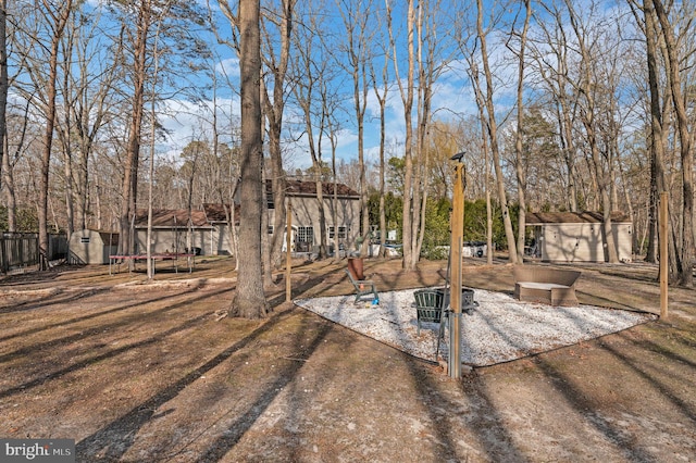 view of yard with an outdoor structure, a storage unit, fence, and a trampoline