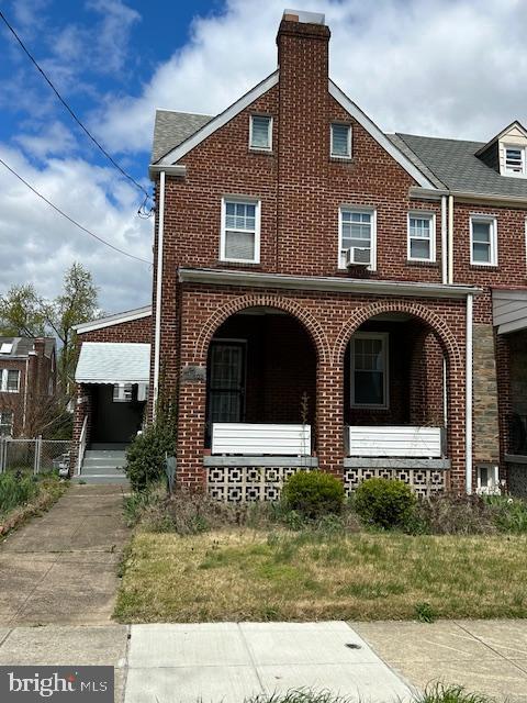 townhome / multi-family property with cooling unit, brick siding, covered porch, and a chimney