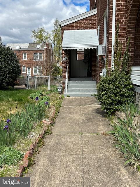 property entrance featuring brick siding and fence