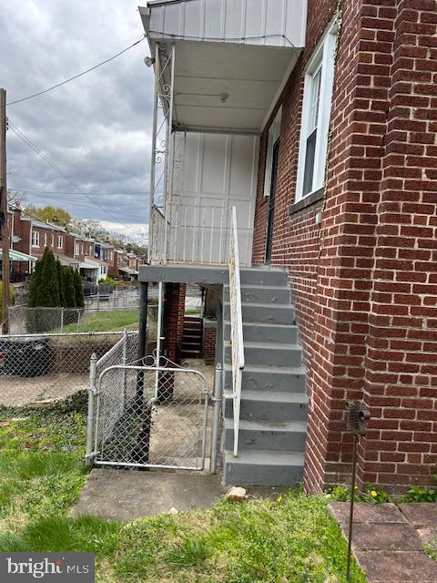 entrance to property featuring fence, brick siding, and a gate