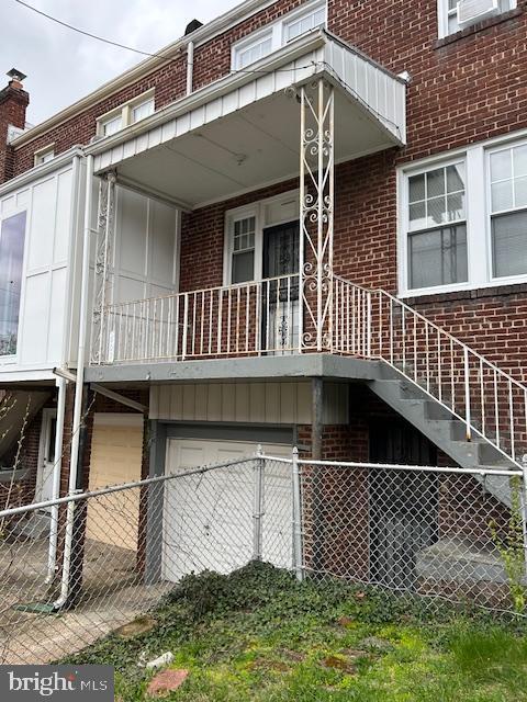 rear view of house featuring brick siding and fence