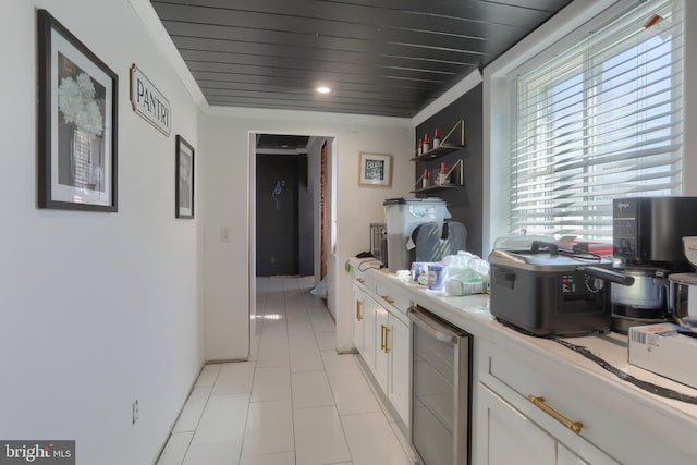 228 Cumberland St, Lebanon, PA 17042 - kitchen featuring crown molding, wine cooler, light countertops, light tile patterned floors, and white cabinetry