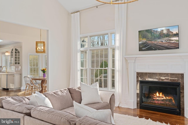 living room with a fireplace, wood finished floors, a towering ceiling, and a chandelier