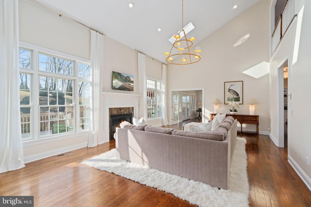 living area featuring visible vents, dark wood finished floors, a premium fireplace, an inviting chandelier, and high vaulted ceiling