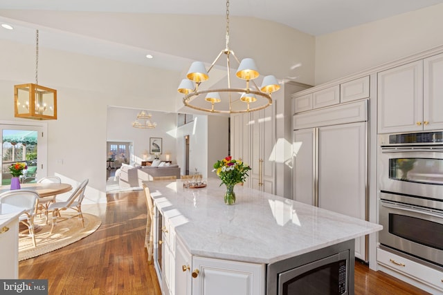 kitchen featuring built in appliances, a notable chandelier, lofted ceiling, and dark wood-style floors