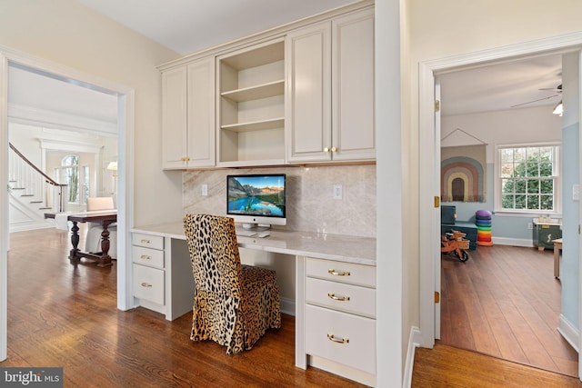 home office with dark wood-style floors, built in desk, baseboards, and a ceiling fan