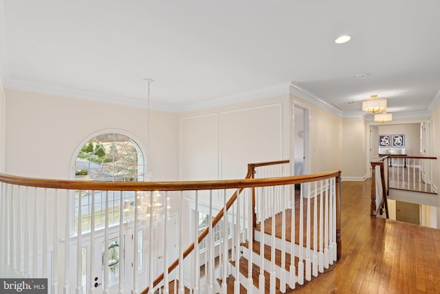 corridor with an upstairs landing, an inviting chandelier, hardwood / wood-style floors, and crown molding