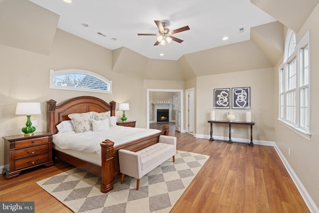 bedroom with vaulted ceiling, multiple windows, light wood-style floors, and baseboards