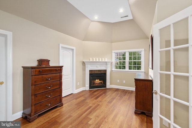 living room with light wood-style flooring, baseboards, a glass covered fireplace, and vaulted ceiling