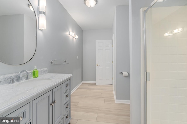 bathroom featuring vanity, a shower stall, baseboards, and wood finish floors