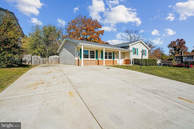 tri-level home featuring brick siding, driveway, a front lawn, and fence