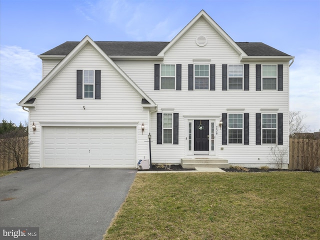 view of front of house with driveway, a front yard, a garage, and fence