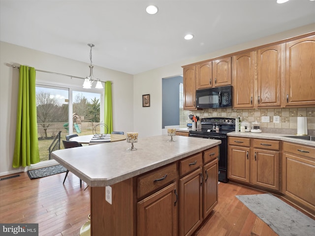 kitchen with light wood-style floors, visible vents, tasteful backsplash, and black appliances