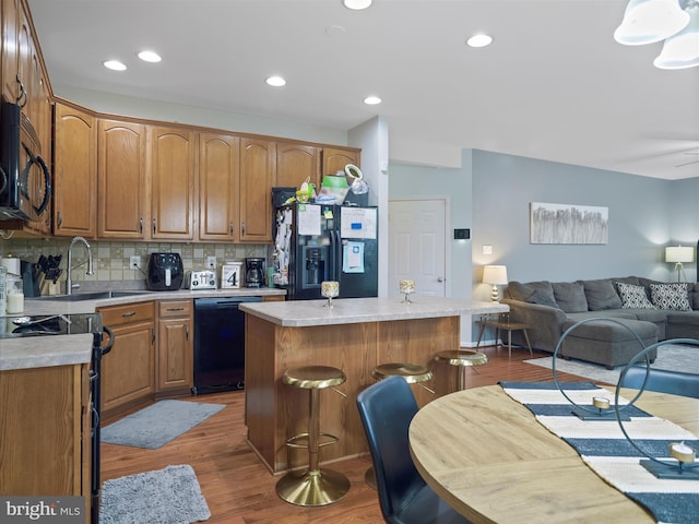 kitchen featuring a center island, dark wood-type flooring, open floor plan, black appliances, and a sink