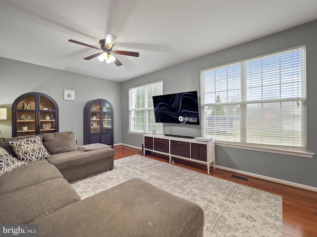 living area featuring visible vents, baseboards, wood finished floors, and a ceiling fan