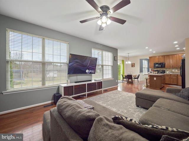 living room featuring wood finished floors, visible vents, baseboards, recessed lighting, and ceiling fan