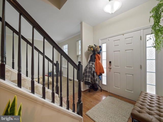 entrance foyer with crown molding, stairway, and wood finished floors