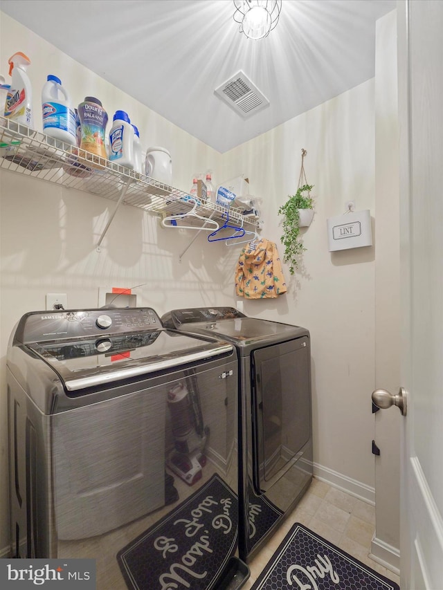 clothes washing area with visible vents, baseboards, separate washer and dryer, and laundry area