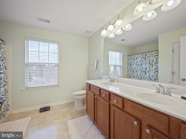 bathroom featuring a sink, visible vents, toilet, and double vanity