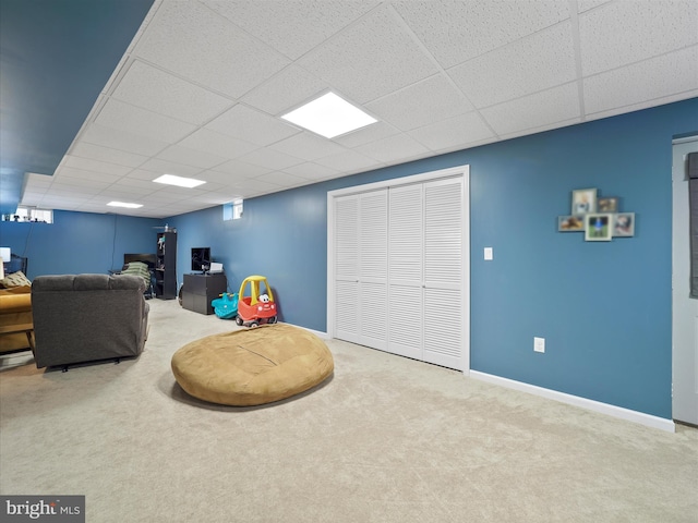 sitting room featuring a drop ceiling, baseboards, and carpet flooring