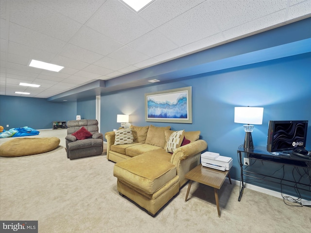 living room featuring a drop ceiling, baseboards, and carpet floors