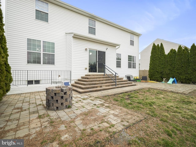 back of property with entry steps, a patio area, and a fire pit