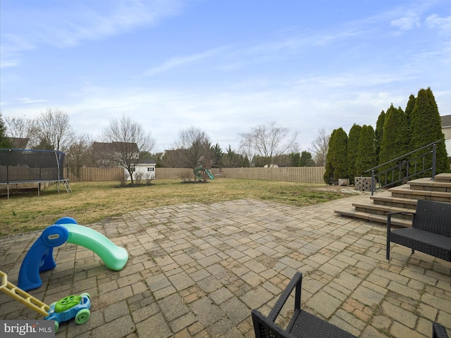 view of patio / terrace with playground community, a fenced backyard, an outdoor structure, a storage shed, and a trampoline