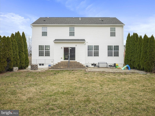 rear view of house with entry steps, a patio area, and a lawn