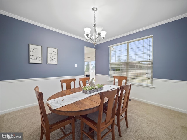 carpeted dining room featuring baseboards, a chandelier, and crown molding