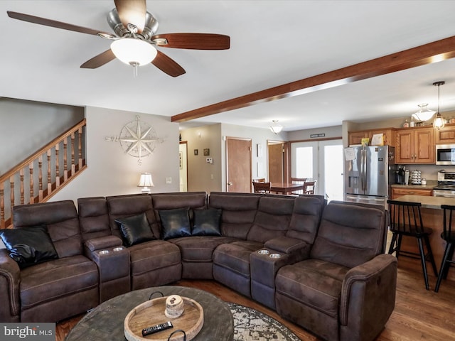 living room with stairs, beam ceiling, wood finished floors, and a ceiling fan