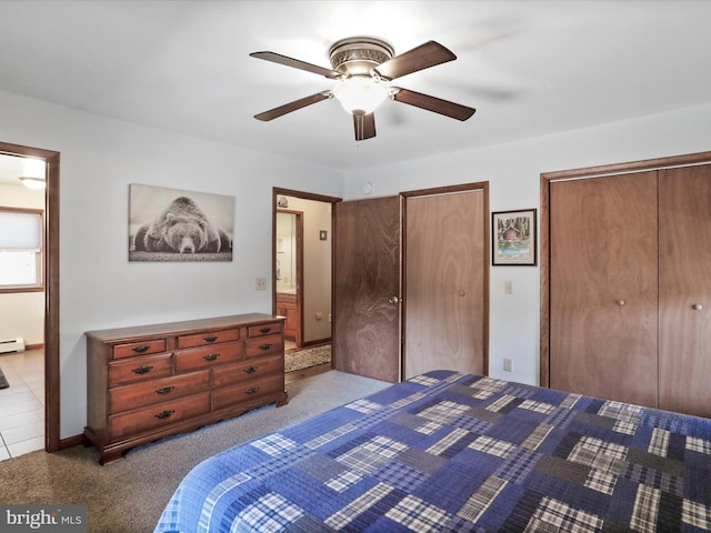 unfurnished bedroom featuring a baseboard radiator, two closets, a ceiling fan, and carpet