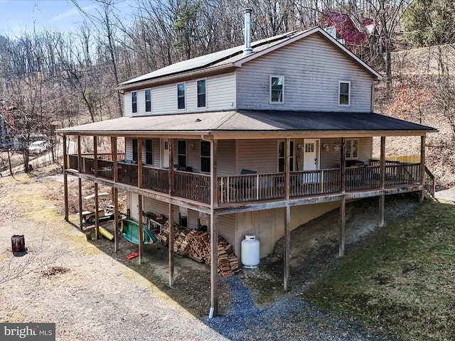 view of front of property featuring an attached garage, covered porch, and roof mounted solar panels