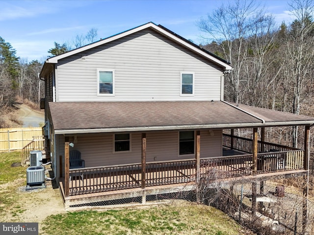 rear view of house featuring a wooden deck, central AC unit, roof with shingles, and fence