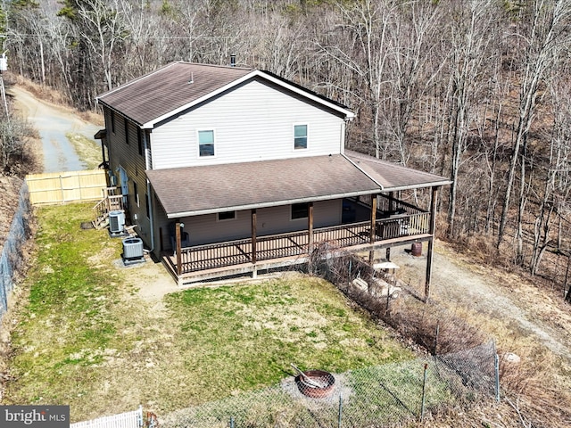 view of front of house featuring a patio, fence, an outdoor fire pit, a front lawn, and central air condition unit