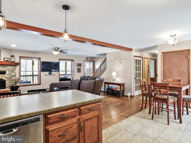 kitchen featuring beam ceiling, ceiling fan, a stone fireplace, dishwasher, and open floor plan