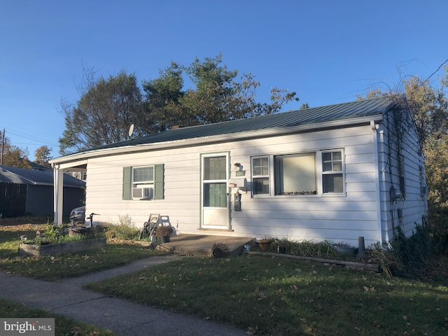 bungalow-style home with an attached carport, cooling unit, metal roof, and a front yard