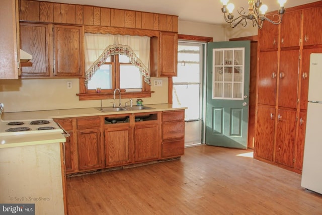 kitchen with a sink, a chandelier, brown cabinetry, and freestanding refrigerator